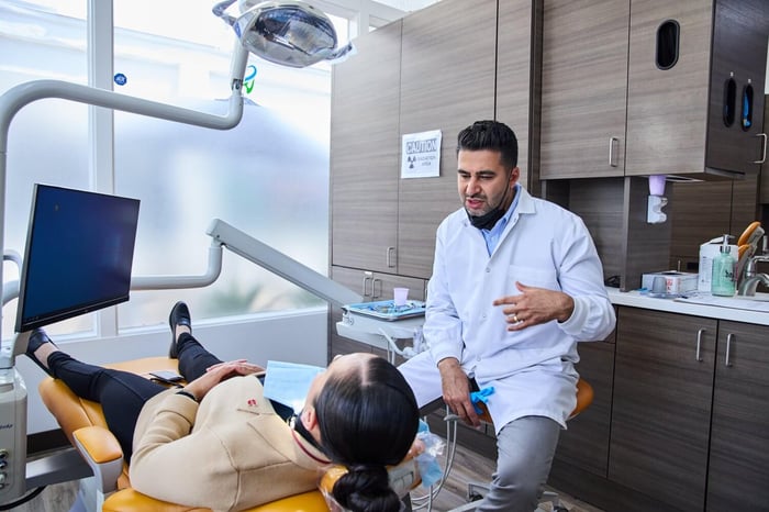 A dentist talking to a patient sitting on a dentist chair