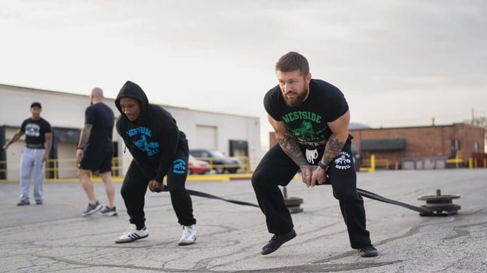 Athletes performing sled duck walks.