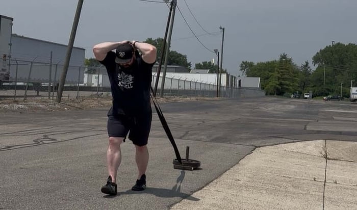 Athlete performing triceps extension with sled.