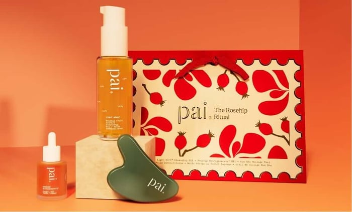 Pai Skincare Rosehip Ritual gift set with orange cleansing oil, red serum, green gua sha tool and rosehip-patterned packaging