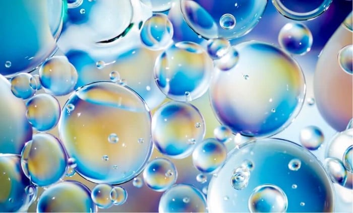 Microscopic bubbles and spheres representing exosomes floating in iridescent blue and golden tones