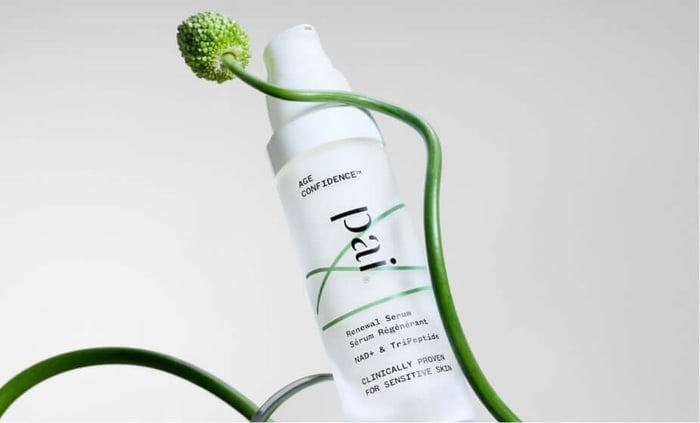 Pai Age Confidence Renewal Serum bottle with decorative green flowering stem on neutral background