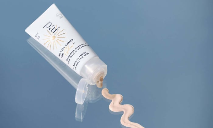 Pai British Summer Time SPF 30 tinted sunscreen tube dispensing peachy-beige mineral formula on blue background