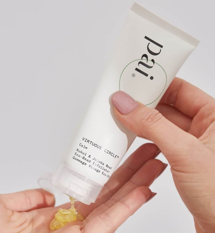 Hands dispensing Pai Virtuous Circle Eco-Bead Exfoliator, showing golden gel texture with jojoba beads for sensitive skin