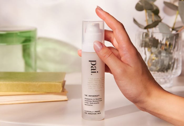 Hand holding Pai The Anthemis Chamomile & Rosehip Soothing Moisturizer bottle for sensitive skin on bathroom shelf