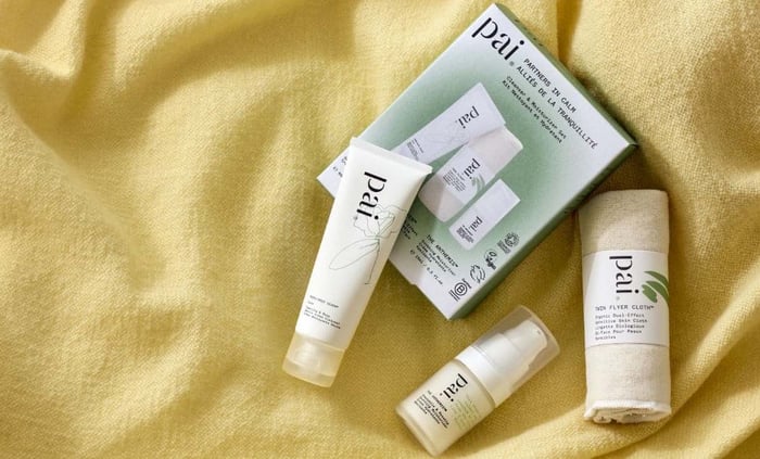 Partners In Calm gift set with Camellia & Rose Gentle Hydrating Cleanser, Anthemis Anti-Redness Serum, and Skin Saviour Cloth on golden yellow textured fabric