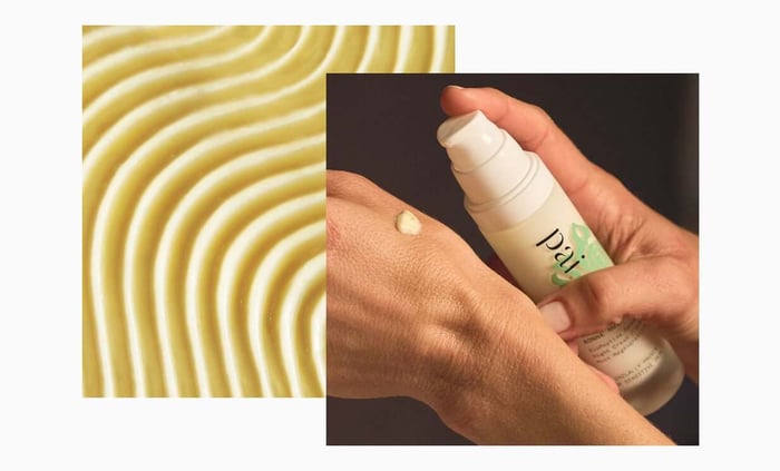 Hand applying Pai Bonne Nuit night serum with creamy texture alongside flowing cream waves background