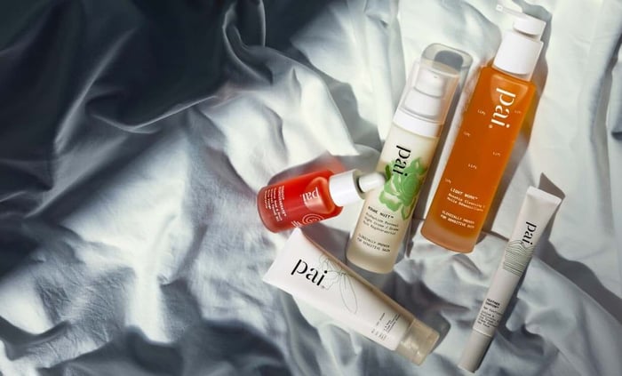 Pai Skincare Bonne Nuit night cream with rosehip oil and cleansers arranged on white linen bedding