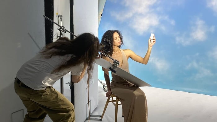 Behind-the-scenes photoshoot of model holding skincare product during Pai Skincare campaign filming with professional camera crew