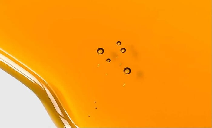 Golden amber rosehip oil with circular bubbles suspended in rich orange liquid