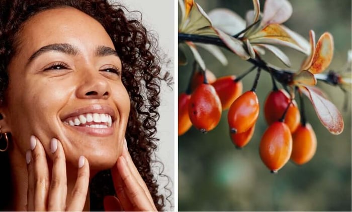 Woman with radiant skin touching her face next to rosehip berries on branch showing natural skincare ingredient source