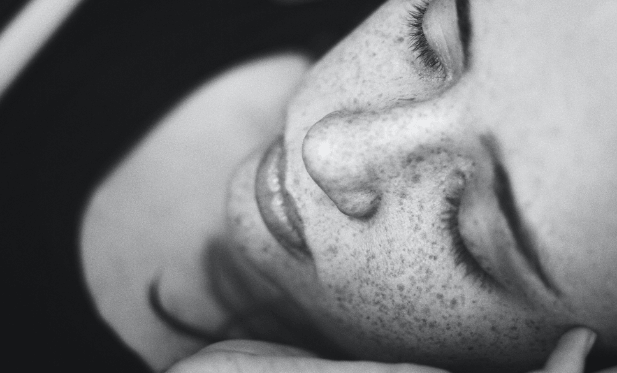 Peaceful woman sleeping on white pillow showing relaxed facial expression in black and white