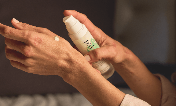 Hands applying Pai skincare serum with a drop visible on skin during nighttime routine