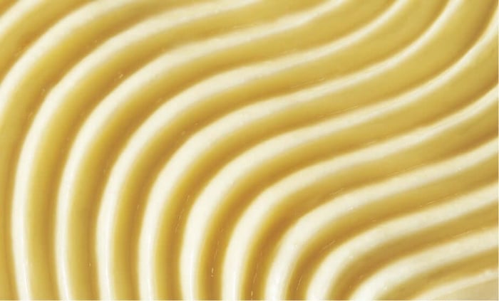 Smooth golden cream texture with flowing ridged pattern showing luxurious night cream formula