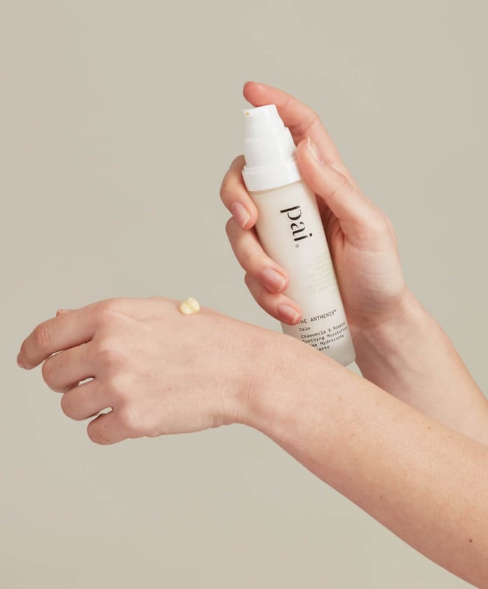 Hands gently holding Pai Chamomile & Rosehip Calming Day Cream with small amount dispensed, showing gentle skincare for sensitive rosacea-prone skin