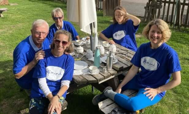 Pai Skincare team members in blue Mind charity t-shirts sitting around outdoor table after mental health awareness walk