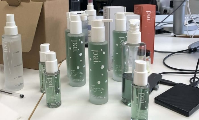 Multiple bottles of Pai Phaze gentle cleanser with distinctive green packaging and white polka dot design in development lab setting