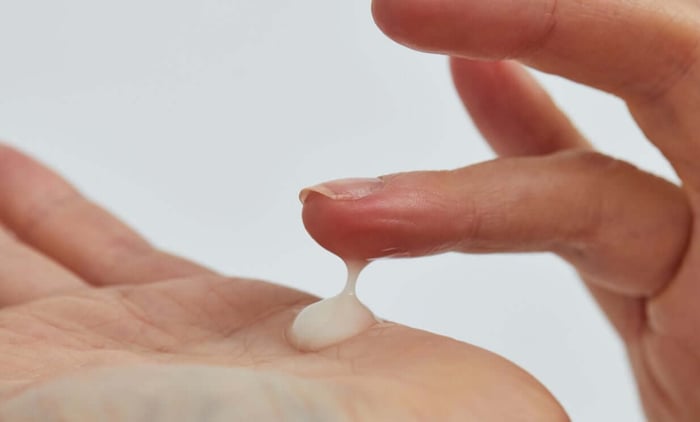 Hands demonstrating clear hyaluronic acid serum texture with gel-like consistency for hydrated skin