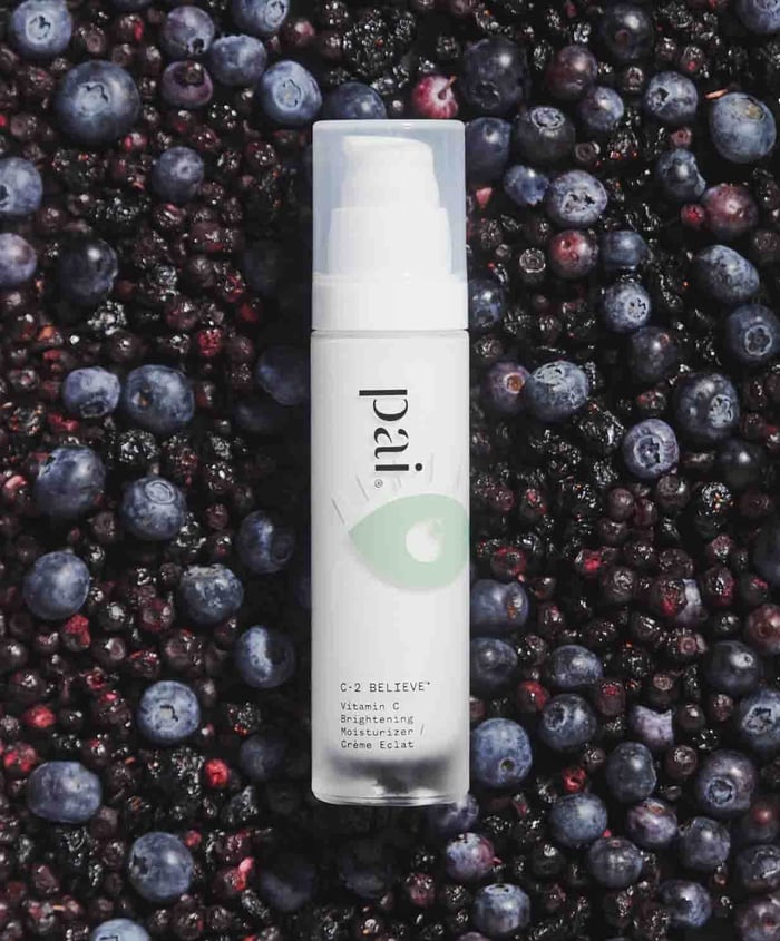 Pai C-2 Believe Vitamin C Brightening Moisturizer surrounded by fresh blueberries and pomegranate seeds