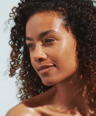 Woman with curly hair showing naturally glowing, hydrated skin after using Century Flower face mist
