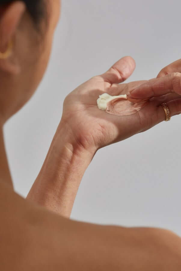 Woman blending cream glow drops in her palm for luminous skin application