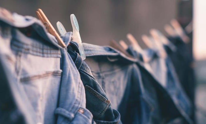 Denim jeans hanging on outdoor washing line with wooden clothespins