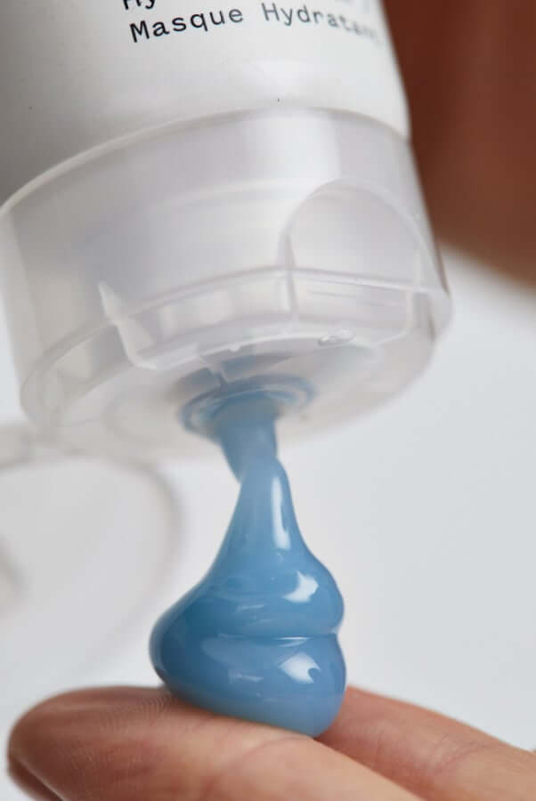 Blue hydrating face mask being dispensed from Resurrection Girl pump bottle onto fingertip