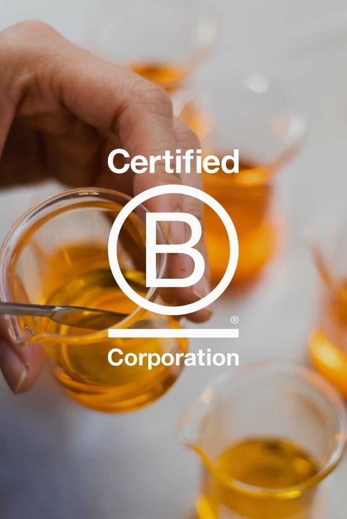 Hands pouring golden face oil with Certified B Corporation logo overlay