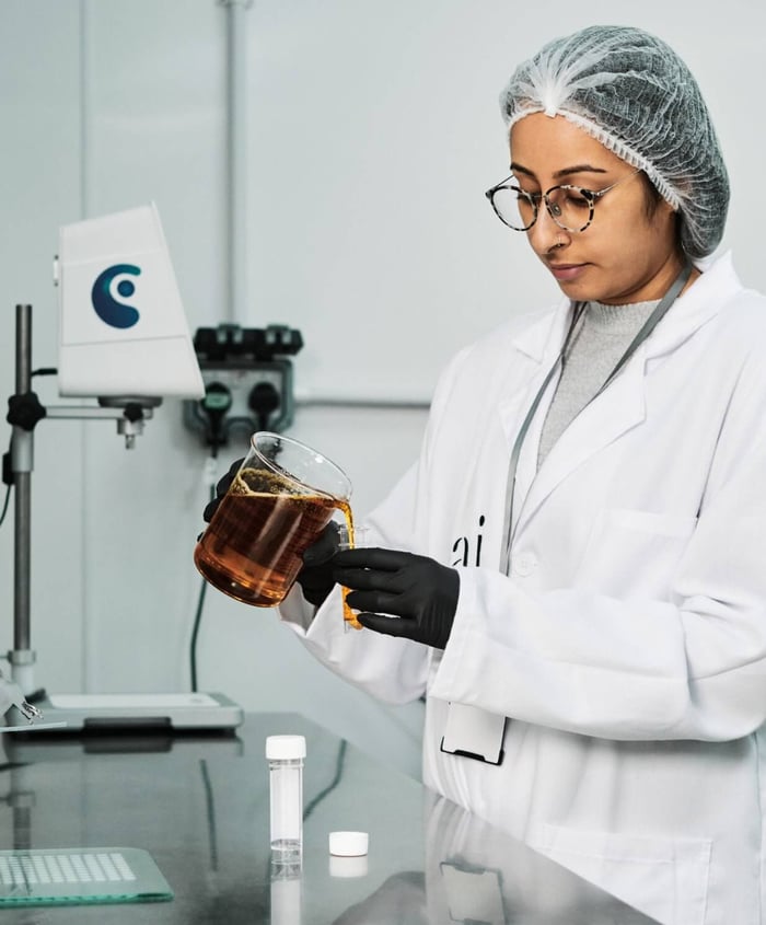 Pai Skincare scientist in laboratory examining amber liquid in glass beaker during product development