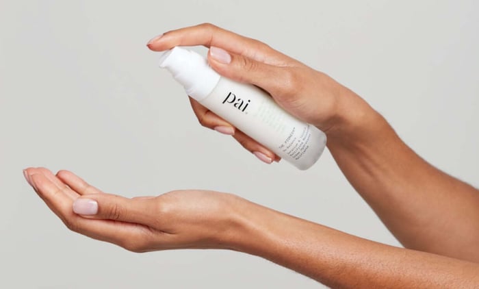 Hands dispensing Pai Light Work Rosehip Cleansing Oil from white pump bottle for acne-prone skincare routine