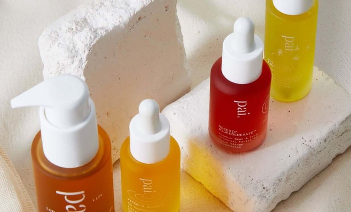 Pai Rosehip BioRegenerate Oil, Carbon Star, and vitamin C concentrates with dropper bottles in warm orange, golden yellow, and red arranged on textured stone