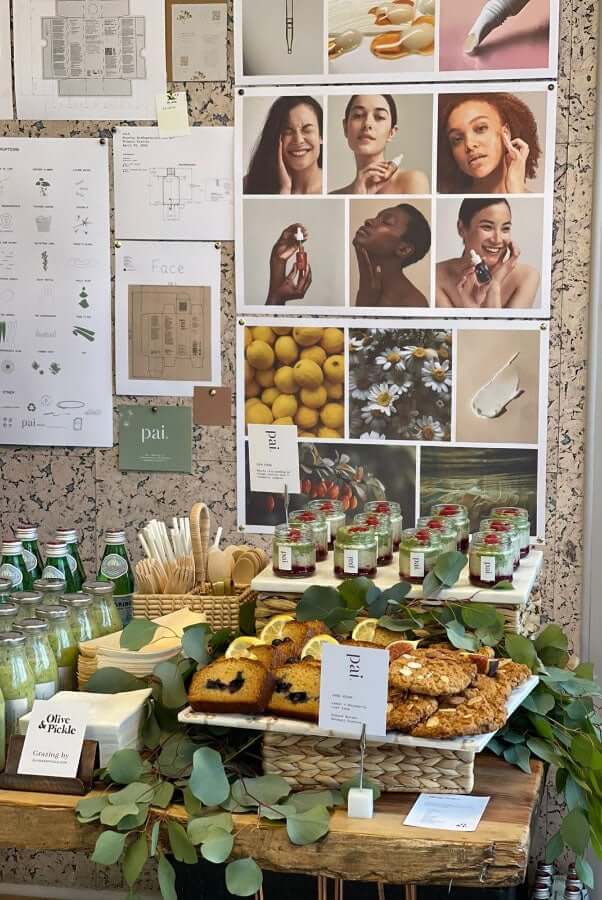 Pai Skincare press day setup with mood boards, product samples, and natural refreshments on wooden table