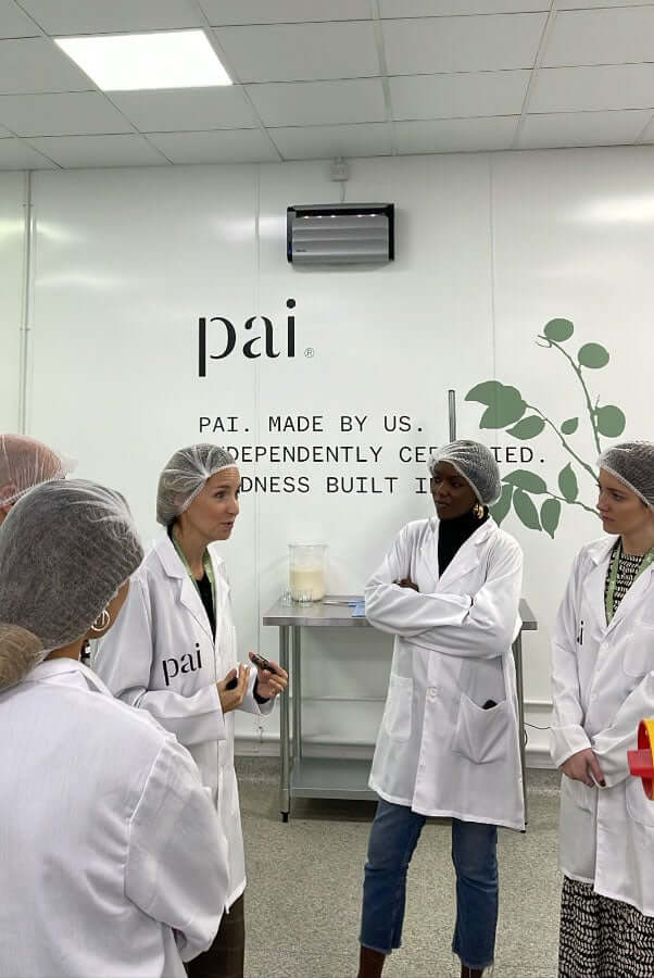 Beauty journalists and editors wearing white lab coats during press visit at Pai Skincare laboratory headquarters