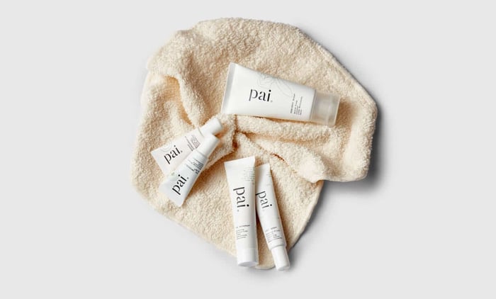 Cream muslin face cloth with four Pai skincare tubes arranged on soft textured fabric