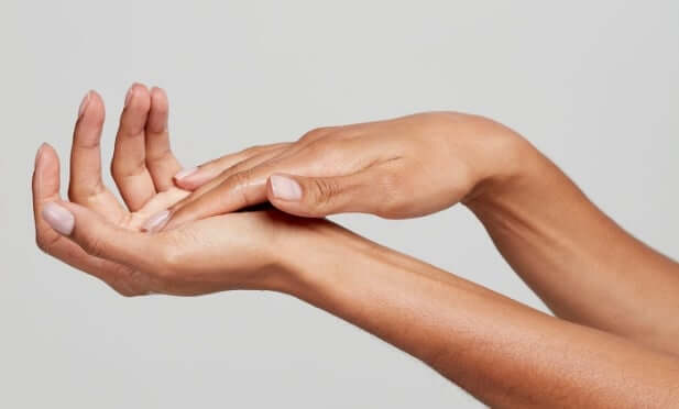 Woman applying skincare product to hands in gentle massaging motion