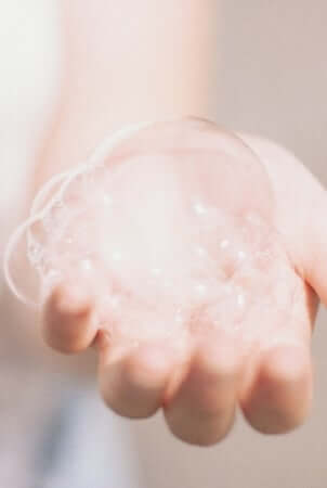 Hands cupping foamy soap bubbles during hand washing routine