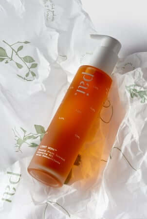 Pai Light Work Rosehip Cleansing Oil bottle surrounded by botanical leaves on white fabric