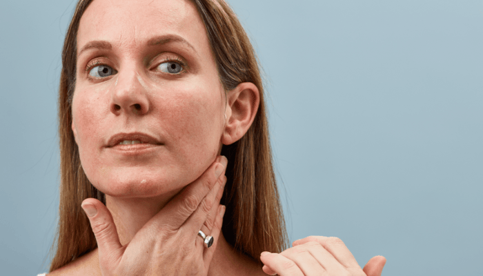 Woman with sensitive skin touching face and neck, demonstrating gentle skincare application