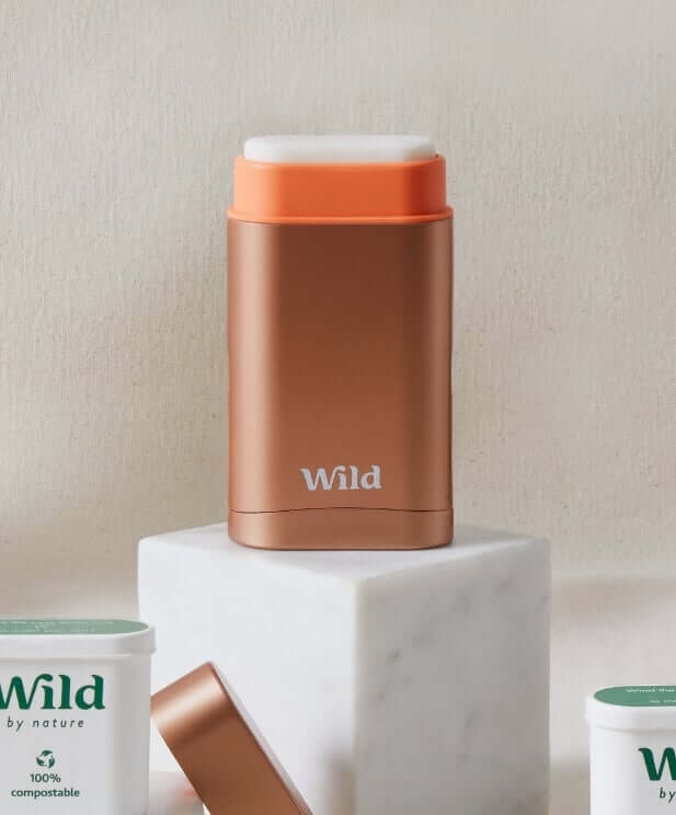 Wild natural deodorant in copper rose gold case with compostable refills on marble platform