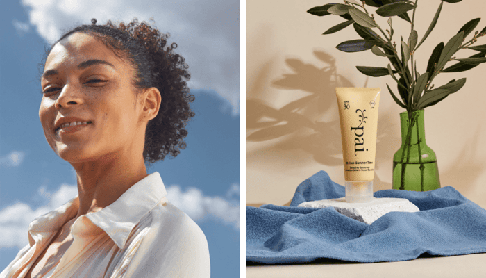 Radiant woman with curly hair enjoys sunshine outdoors next to Pai British Summer Time SPF30 tube with blue cloth and olive branch on neutral background