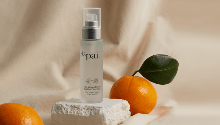 Pai BioAffinity Tonic spray bottle with pump dispenser beside fresh oranges and white towel on neutral background