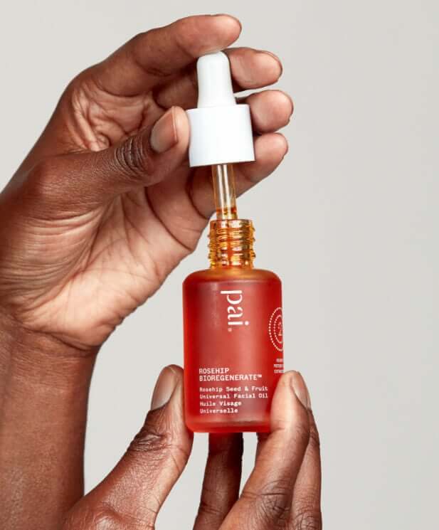 Hands holding Pai Skincare Rosehip BioRegenerate Oil bottle with white dropper cap