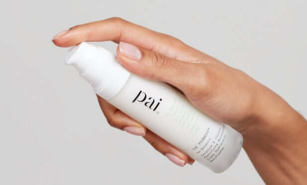 Hand holding Pai Pioneer Gentle Foaming Cleanser against soft grey background