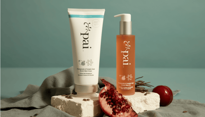 Pai Pomegranate & Pumpkin Seed Stretch Mark System with cream tube and oil bottle alongside pomegranate and natural styling elements