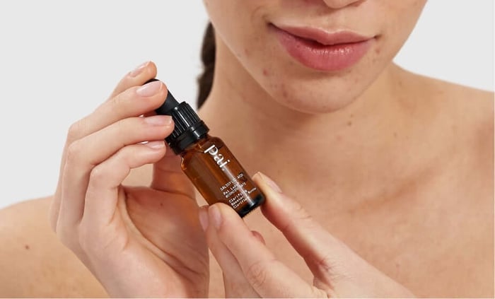 Model holding Pai Salicylic Acid Booster for sensitive skin with amber glass bottle and black dropper