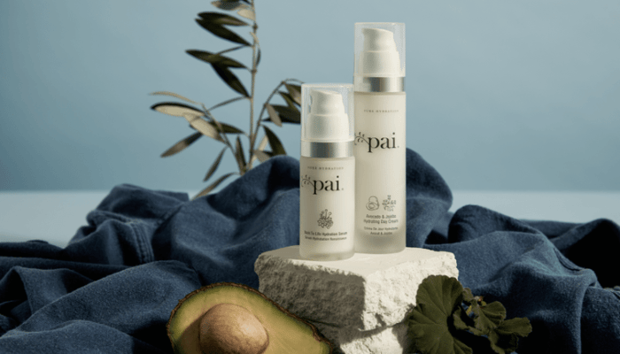 Pai Back to Life Hydration Serum and Love And Haight Hydrating Moisturiser arranged on white stone with fresh avocado, blue linen backdrop