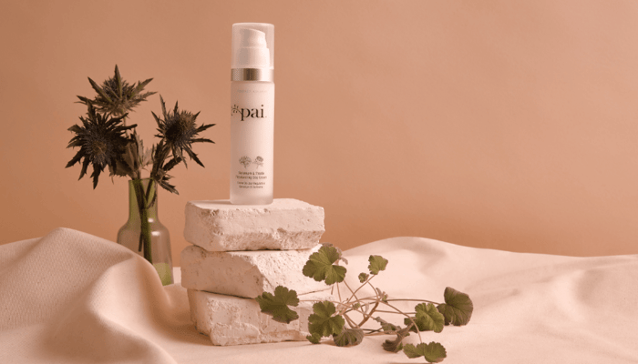 Pai Skincare Copaiba & Zinc Perfect Balance Blemish Serum displayed on stacked natural stone blocks with fresh botanicals against warm terracotta backdrop