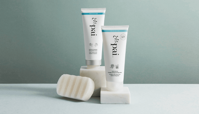 Pai Skincare Comfrey & Calendula Calming Body Cream tubes with white soap bars on sage green background