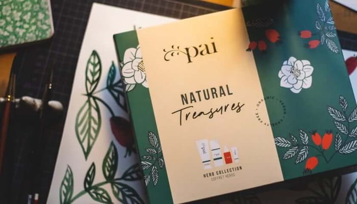 Pai Natural Treasures gift collection packaging featuring botanical illustrations of white camellias and green leaves on cream and dark green backgrounds