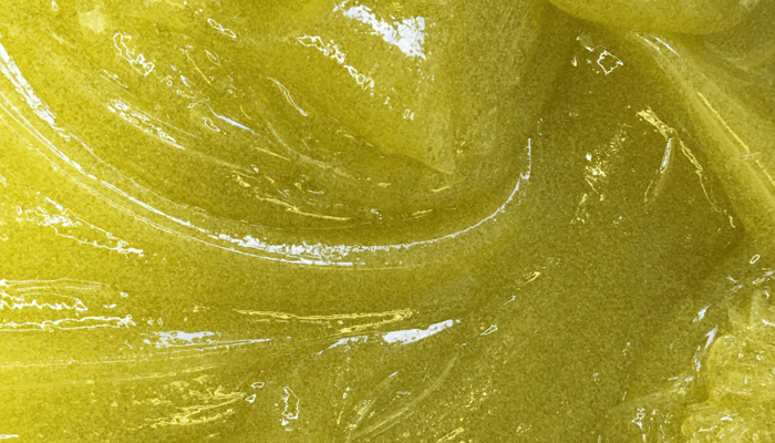 Close-up texture of golden Kukui & Jojoba Bead Skin Brightening Exfoliator showing smooth spherical jojoba beads for sensitive skin